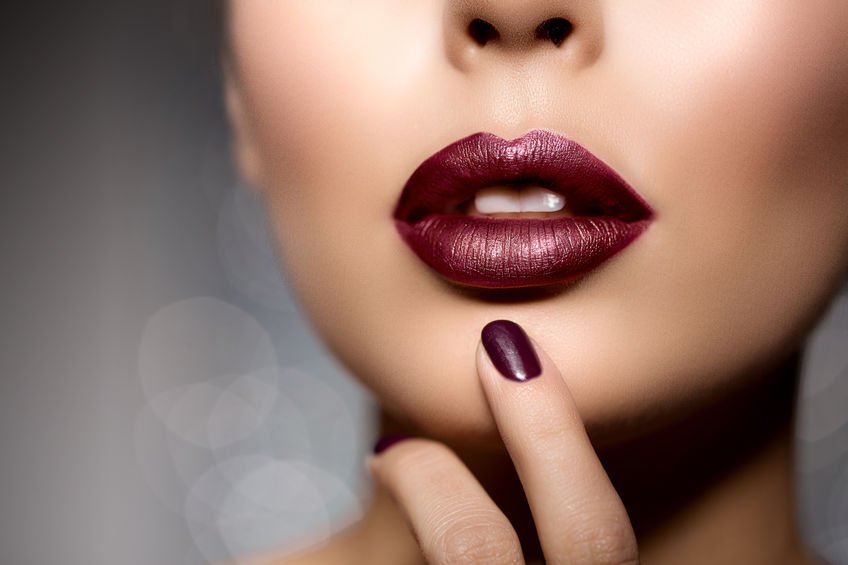red woman lips close up. beautiful model girl with lipstick, manicure thinking about lip filler risks