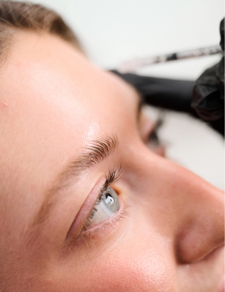 Woman receiving professional eyebrow microblading treatment at beauty salon with specialized tool - Botox and Wrinkle relaxers in Alpharetta, GA