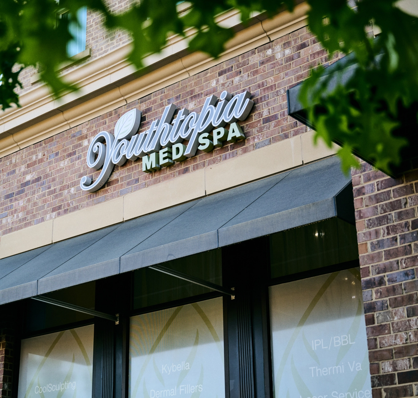 Radiance Med Spa exterior signage on brick building with modern storefront and foliage - in Alpharetta, GA