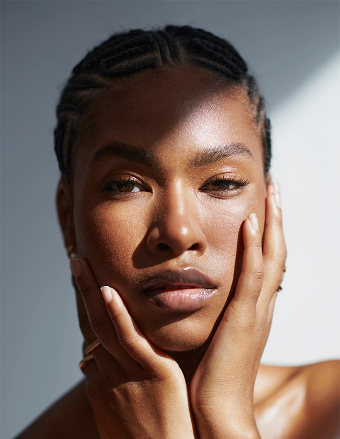 Woman with glowing skin touching face in natural light, showcasing skincare and beauty routine results - Skinpen Micro-Needling in Alpharetta, GA