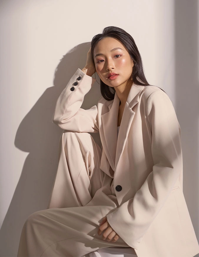Woman in white oversized blazer and pants sitting in natural light with dramatic shadow - Thorne in Alpharetta, GA